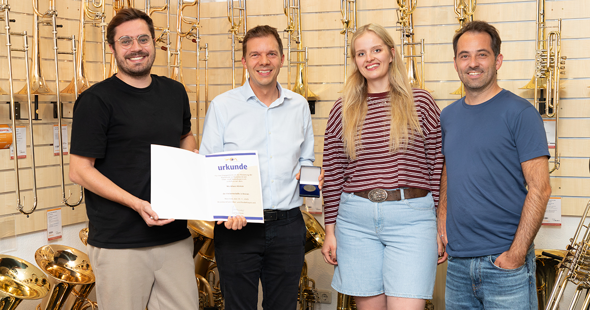 Geschäftsführer Andreas Kirstein und Roman Thomas mit der Urkunde und der Fördermedaille des MON. Mit auf dem Foto: Carolin Köpf und Stephan Echtler aus der Bläserabteilung des Musikhaus Kirstein.