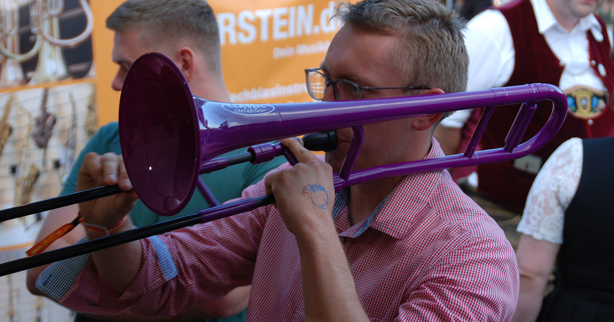 Ein Besucher der Brass Wiesn 2025 testet eine MardiBrass-Kunststoffposaune an.