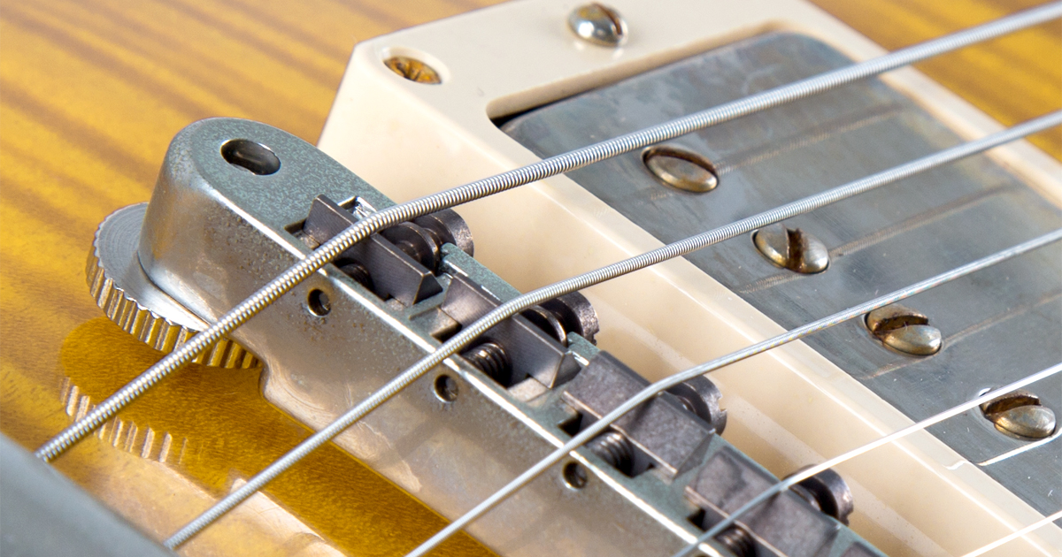 Detailaufnahme: Saiten einer E-Gitarre mit und ohne Umwicklung.