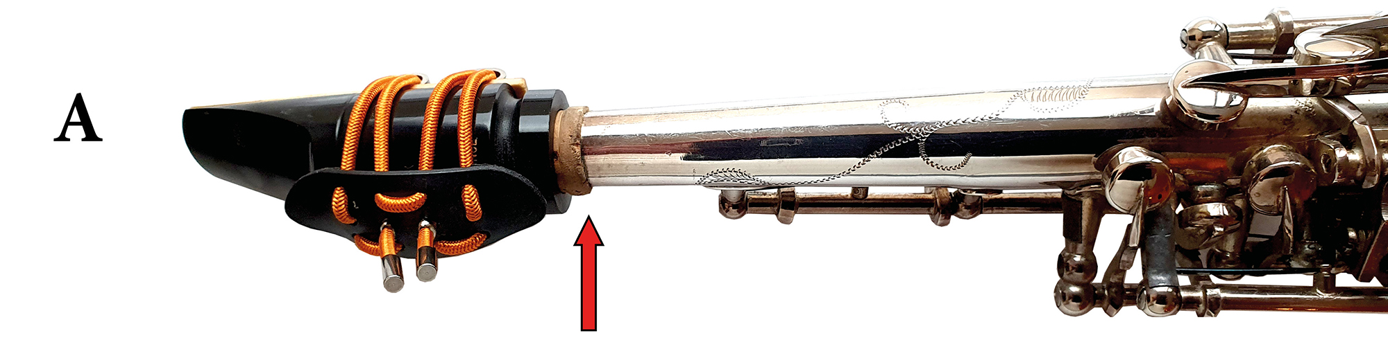 Ein Saxophon ohne Klangbrücke. Ein roter Pfeil zeigt auf die Klemmstelle zwischen Mundstück und Instrument.