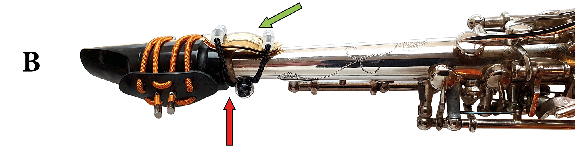 Ein Saxophon mit Klangbrücke. Ein roter Pfeil zeigt auf die Klemmschnittstelle, ein grüner Pfeil zeigt auf die Klangbrücke.